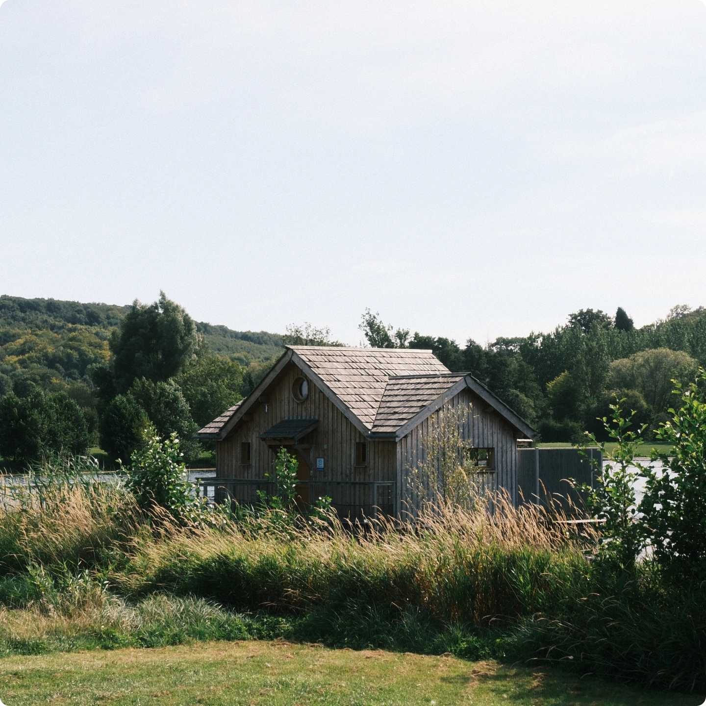Cabane en bois au toit de bardeaux au bord d'un lac, collines boisées