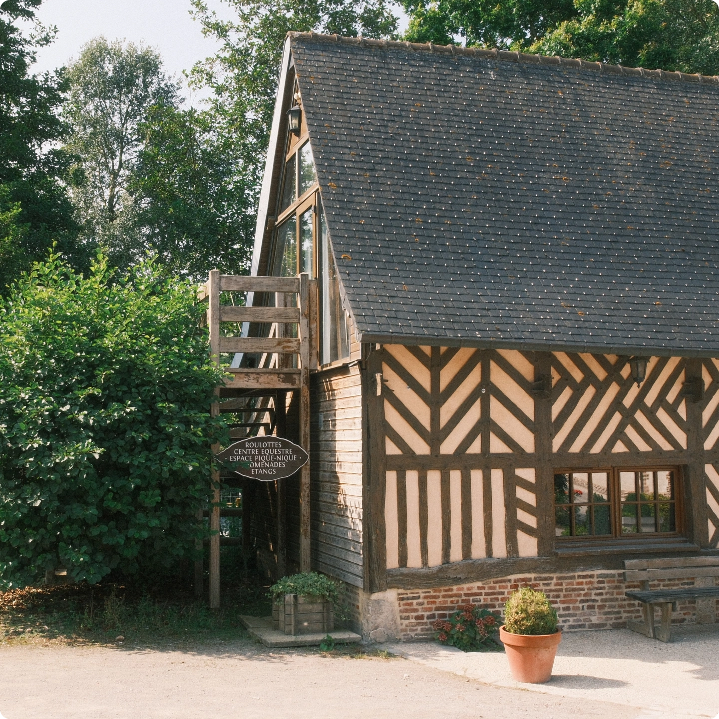 Grange à colombages avec panneau indiquant centre équestre, étangs et promenades