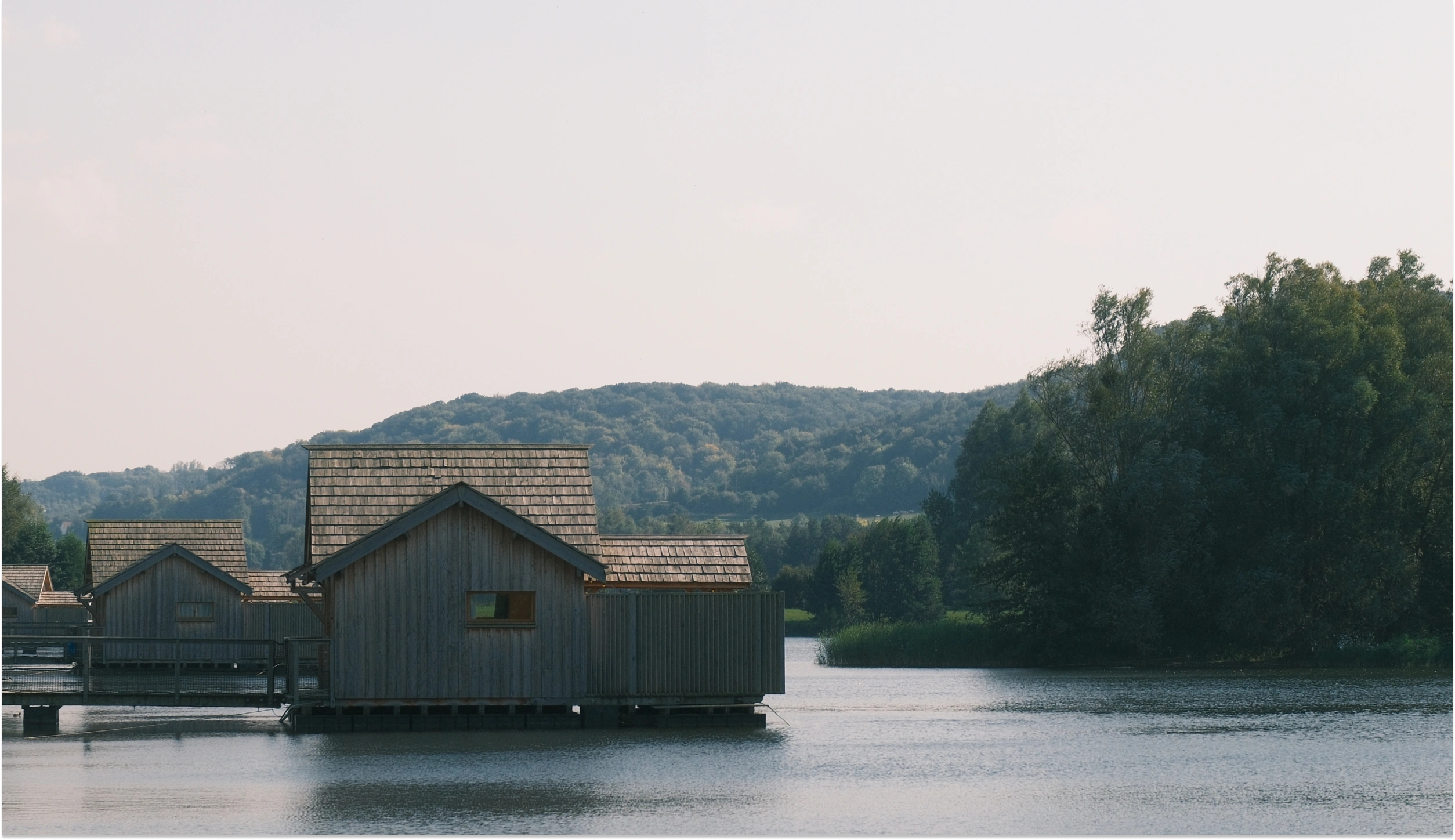Cabanes en bois sur pilotis au-dessus du lac, colline boisée
