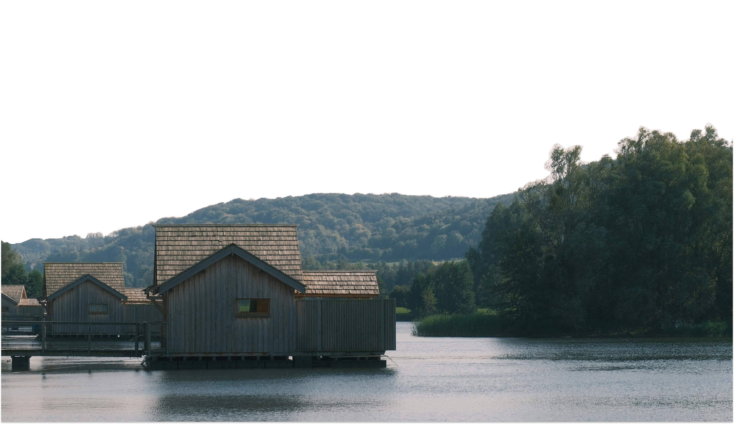 Cabanes en bois sur pilotis au-dessus du lac, colline boisée