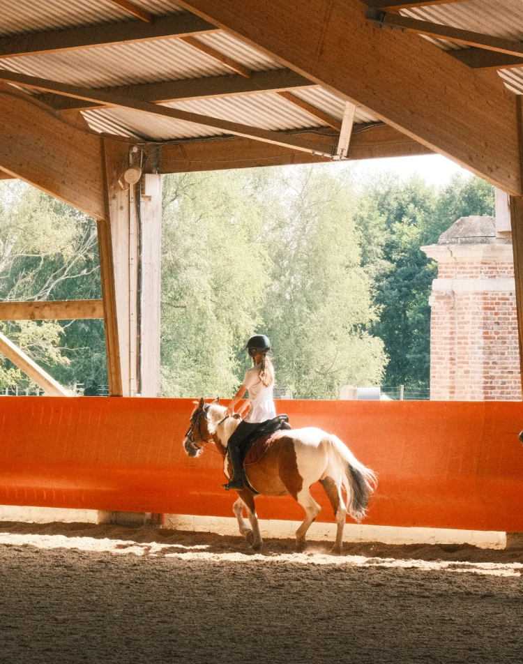 Young rider on a piebald pony in a covered riding arena
