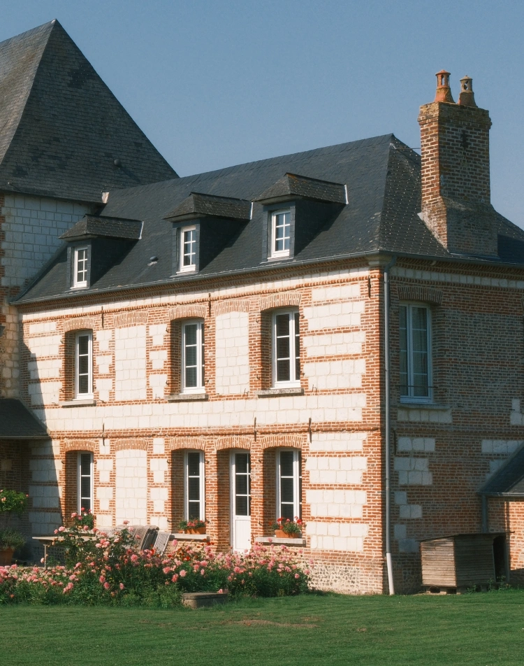 Maison normande en brique et pierre fleurie de rosiers