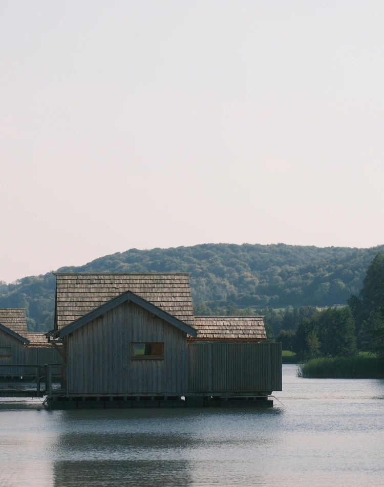 Cabanes en bois flottant sur un étang devant une colline boisée