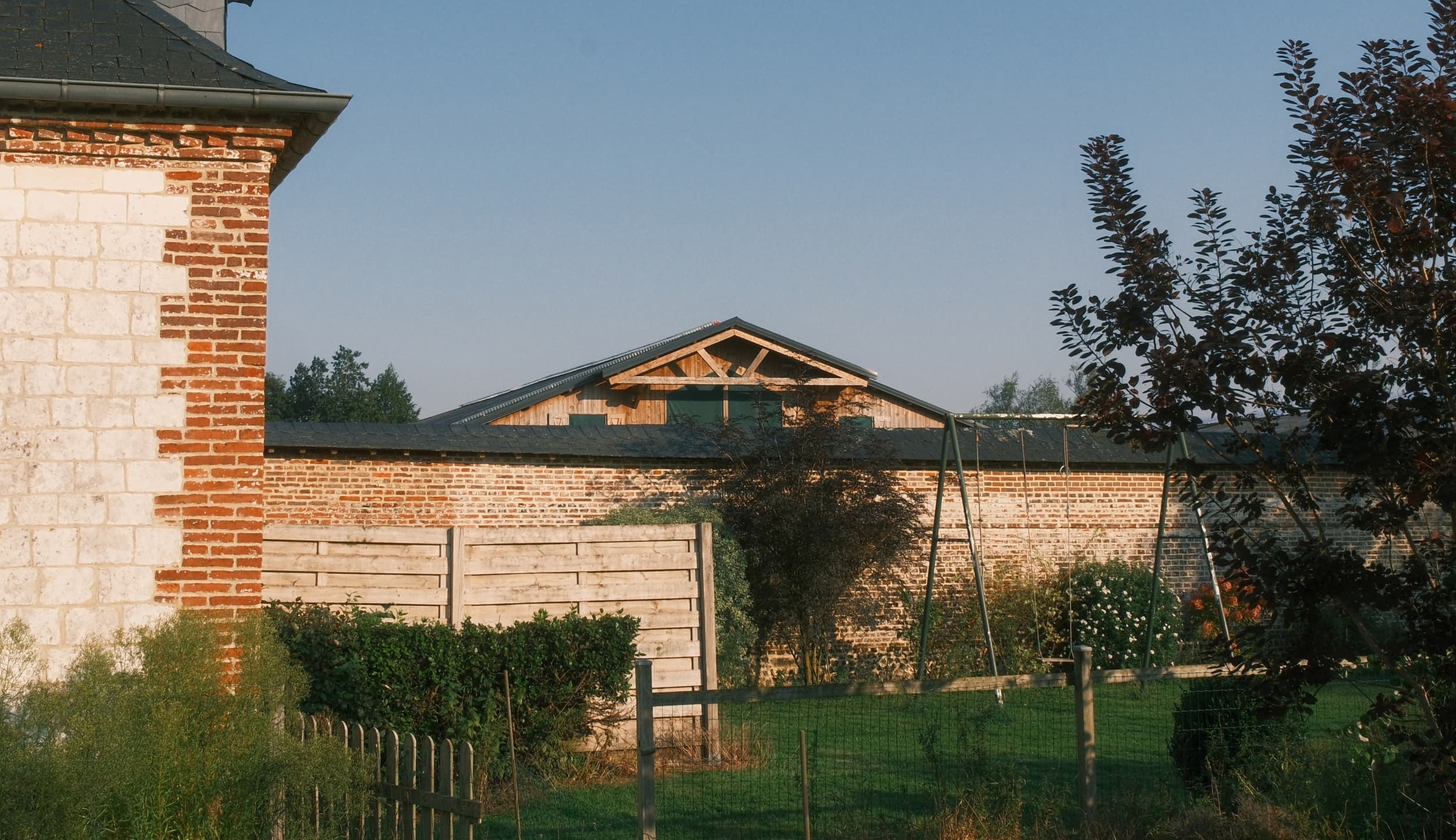 Brick wall and stone building with a gabled wooden structure behind
