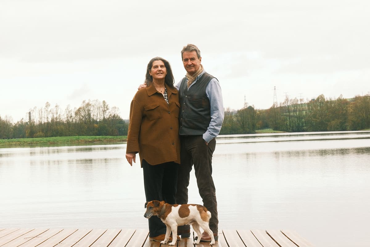 Jérôme Maillard and Marie-Annick de Thézy standing with their dog in front of one of the estate's ponds.